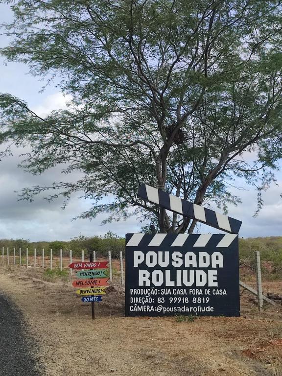 Entrada da Pousada Roliúde com claquete e placas de boas-vindas em vários idiomas