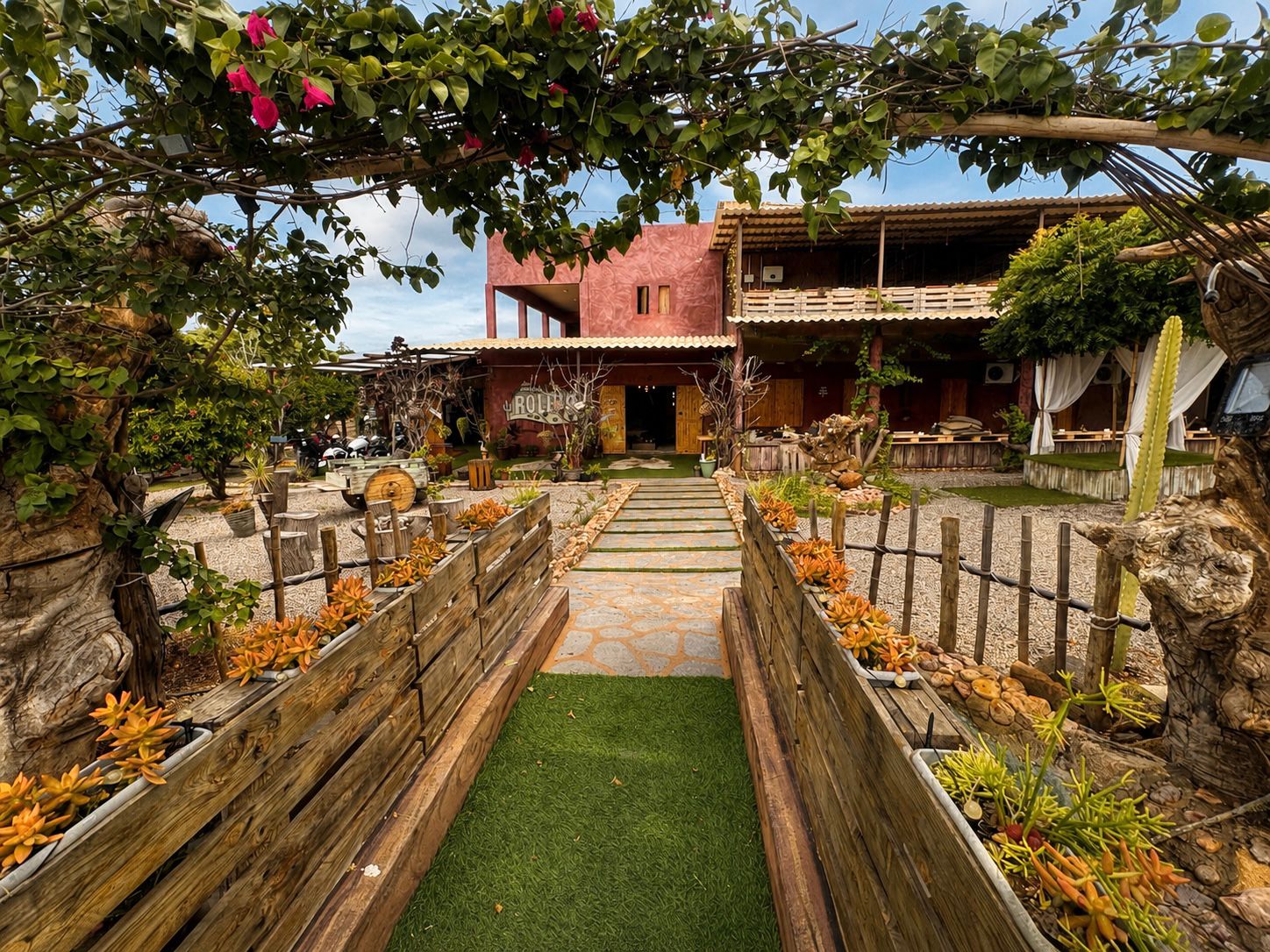 Jardim da entrada da Pousada Roliúde com flores e caminho de pedras